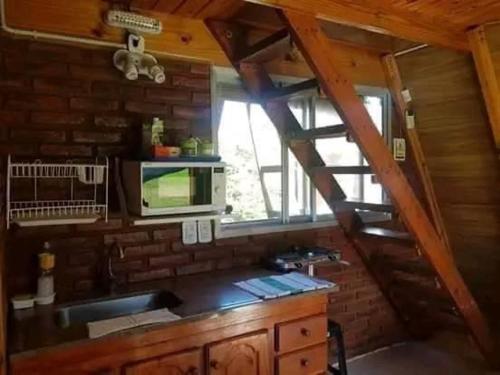 una cocina con microondas y una ventana en una cabaña en Cabañas Alpinas Obligado en San Pedro