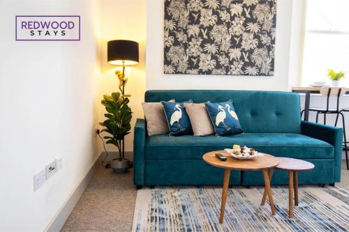 sala de estar con sofá azul y mesa en Modern 1 Bed 1 Bath Apartment for Corporates & Contractors, FREE Parking, Wi-Fi & Netflix By REDWOOD STAYS, en Farnborough