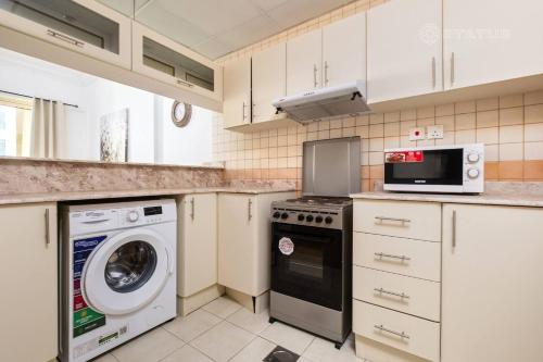 a kitchen with a washing machine and a microwave at Marina View Manchester tower in Dubai