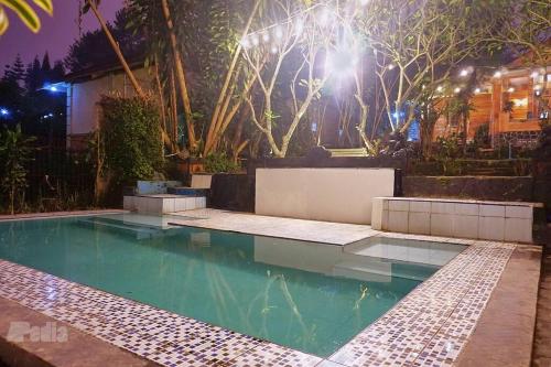 a swimming pool in a backyard at night at Villa Tentram Puncak, 6 Kamar, Billiar, Karaoke in Paragajen