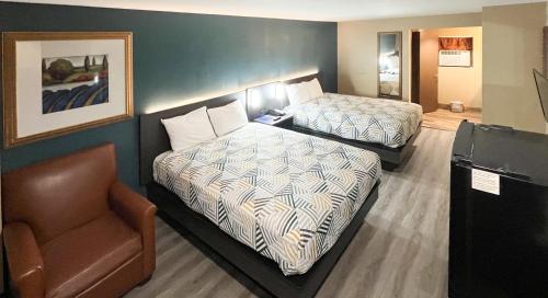 una habitación de hotel con 2 camas y una silla en Motel 6-Snyder, TX, en Snyder