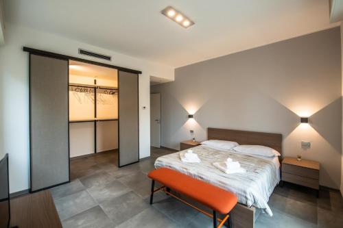 a bedroom with a large bed and a orange chair at G12 B&B l Zona Ospedale Maggiore & Centro l Parking Privato Gratuito in Parma