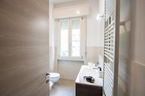 a bathroom with a toilet and a sink and a window at GG12 Parma Comfort & Parking Suites in Parma