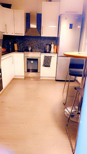 uma cozinha com armários brancos e piso em madeira em Room in Helsinki area em Helsinque
