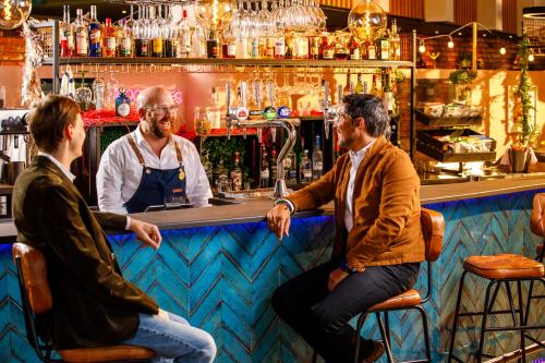 a group of three men sitting at a bar at Novotel London Greenwich in London