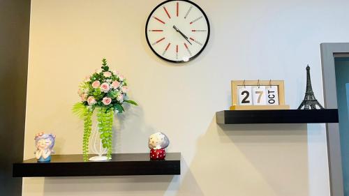 a clock on a wall with a vase of flowers on a shelf at The base Central Pattaya 271 by Numam in Pattaya Central