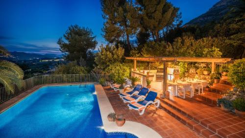 a swimming pool with chairs and a gazebo at Casa Chilango in Montgo