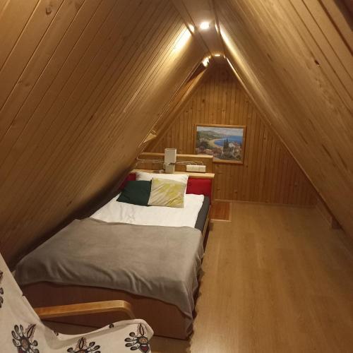 a small bedroom with a bed in a attic at Tu i Teraz - domek in Bukowina Tatrzańska