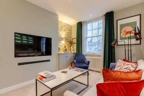 een woonkamer met een tafel en een televisie bij Elegant 1BD Flat in the Heart of Notting Hill! in Londen