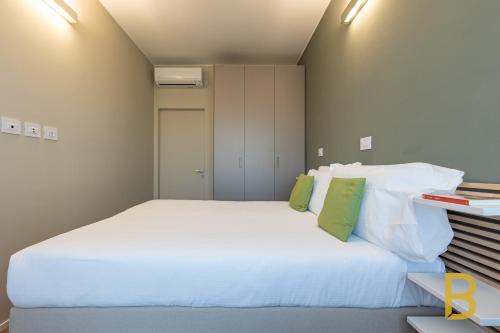 BePlace Apartments in Primaticcio في ميلانو: غرفة نوم بسرير ابيض كبير مع مخدات خضراء