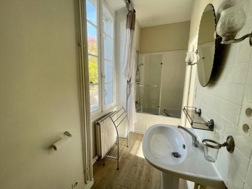 ein weißes Bad mit einem Waschbecken und einem Fenster in der Unterkunft Au bord de la Vézère in Le Bugue