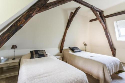 2 Betten in einem Zimmer mit Holzbalken in der Unterkunft Au bord de la Vézère in Le Bugue