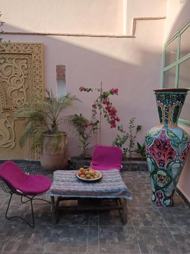 un patio con sillas moradas, una mesa y un jarrón en Riad tania mozaik, en Taroudant