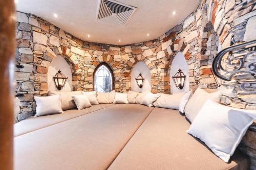 a living room with a large couch in a stone wall at Traumhotel Alpina Superior Yoga Ayurvedahotel in Gerlos