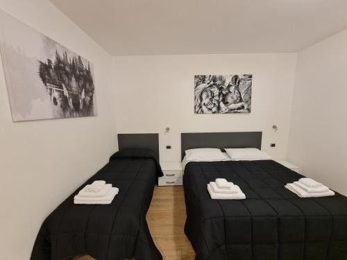 アルゲーロにあるMonti Guest House Algheroの白い部屋のベッド2台(黒いシーツ付)