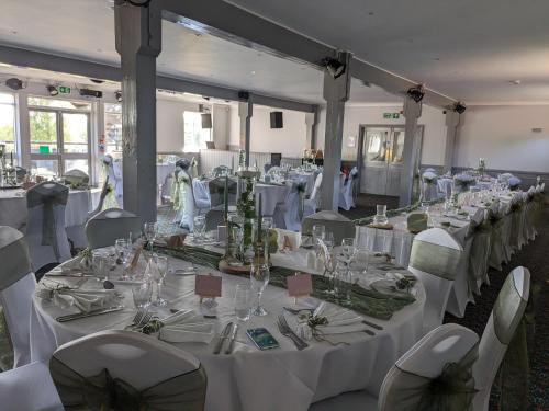 Lakeside Lodge في Pidley: غرفة مليئة بالطاولات والكراسي مع مفارش المائدة البيضاء