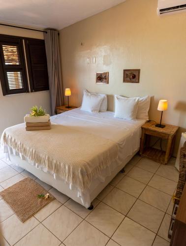 a bedroom with a large bed with white sheets and pillows at Pousada Vila Canoa in Canoa Quebrada