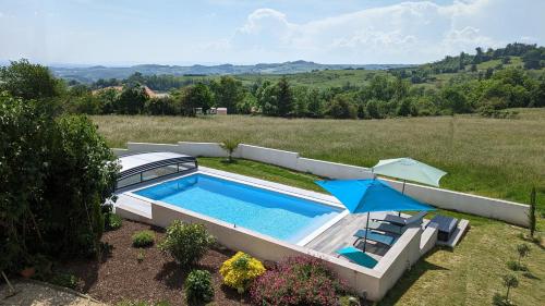 une piscine dans une cour avec un parasol dans l'établissement Chez Nancy, à Montmiral
