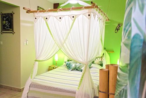 a bedroom with a canopy bed with white curtains at Ti Plèn Kréol in Pointe-Noire