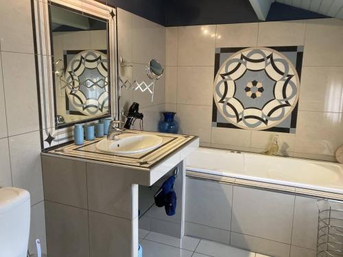 ein Badezimmer mit einem Waschbecken, einer Badewanne und einem Spiegel in der Unterkunft Villa en front de mer in Narbonne-Plage