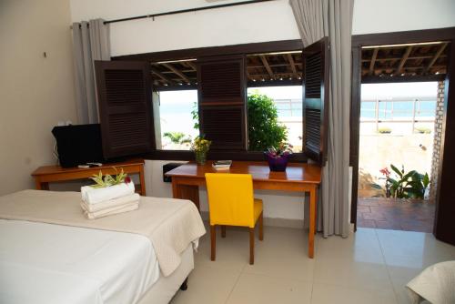um quarto com uma secretária e uma mesa com uma cadeira amarela em Pousada Vila Canoa em Canoa Quebrada