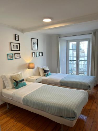 deux lits dans une chambre blanche avec une fenêtre dans l'établissement FADO Bairro Alto - SSs Apartments, à Lisbonne