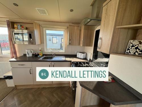 a small kitchen with wooden cabinets and a sink at Abi in Selsey
