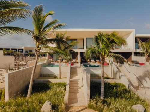 a house on the beach with palm trees at Nobu Hotel Los Cabos in Cabo San Lucas