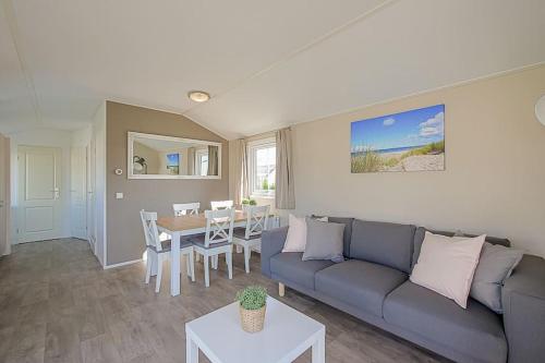 un soggiorno con divano e tavolo di Chalet Luttikduin 22, met ruime tuin! - Callantsoog a Callantsoog