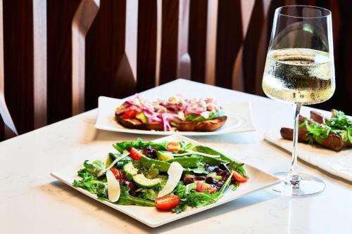 a table with two plates of food and a glass of wine at AC Hotel Houston Downtown in Houston