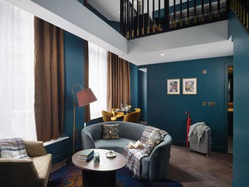 a living room with blue walls and a couch and a table at The Other House South Kensington in London