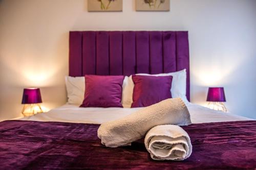 a bedroom with a large bed with purple sheets and pillows at Stylish 2 Bed City Centre Apartment with Sofa Bed - FREE Parking, Coffee Machine, Netflix & Alexa in Sheffield