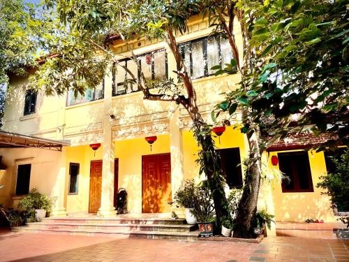 a yellow building with a tree in front of it at Lee Homestay in Hanoi