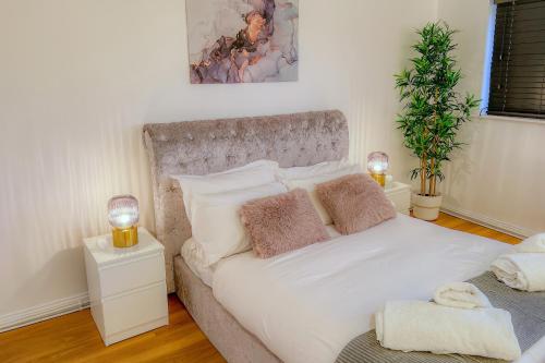 a bedroom with a large white bed with two lamps at Deluxe 2 Bed Apartment- Near Heathrow, Legoland, Windsor Slough in Slough