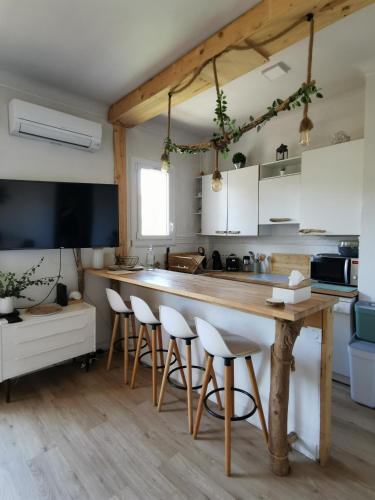 - une cuisine avec une grande table en bois et des tabourets dans l'établissement T3 avec terrasse à 200 mètres de la mer, à Canet