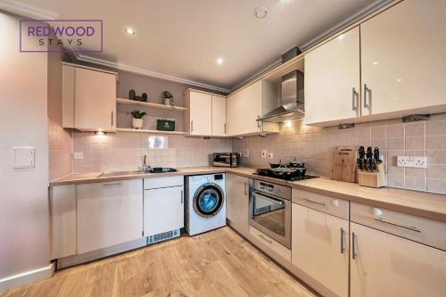 a kitchen with white cabinets and a dishwasher at Spacious 2 Bed 2 Bath Apartment, Near Train Station, FREE Parking By REDWOOD STAYS in Woking