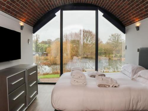 a bedroom with a large bed and a large window at The Tunnel at Bridge Lake Farm and Fishery in Banbury