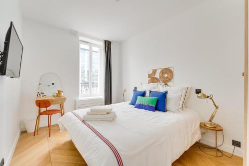 um quarto branco com uma cama grande e almofadas azuis em PorteMaillot & La Défense 4 Bedroom 10 people em Neuilly-sur-Seine