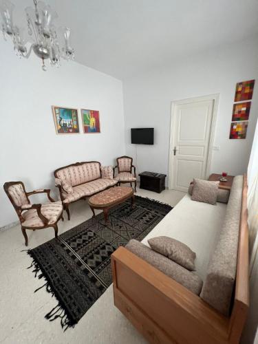 a living room with a bed and a couch and chairs at Maison Ghemrini in Sidi Bou Saïd