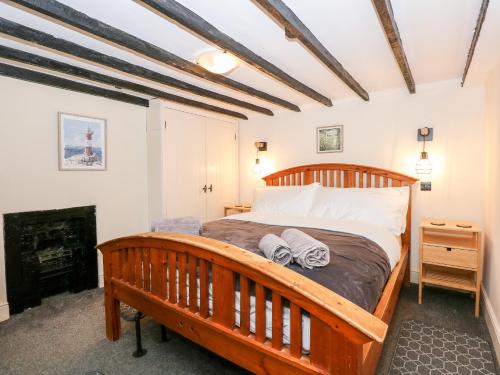 1 dormitorio con cama de madera y chimenea en Butterfly Cottage en Alford