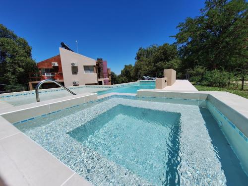 a swimming pool with blue water in front of a house at COSTA COM Departamentos de Montaña in Merlo