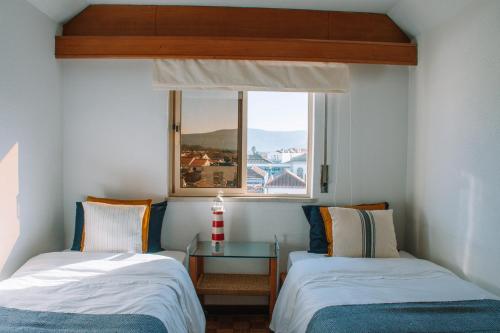 Duas camas num pequeno quarto com uma janela em Just Like Home - AP da Costa em Caminha