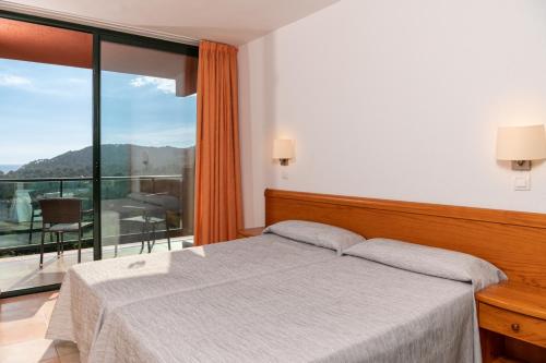 een slaapkamer met een bed en een groot raam bij Albamar Apartaments in Lloret de Mar