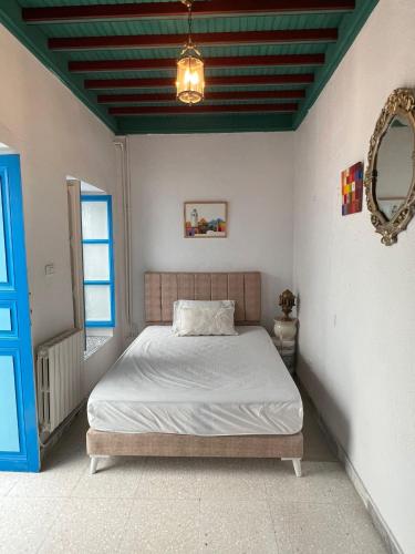 a bedroom with a bed and a blue door at La maison 4 puits in Sidi Bou Saïd