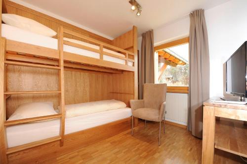 a room with bunk beds and a chair and a television at Kleiner Turm 02 in Schruns