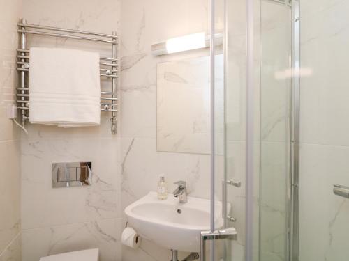 a white bathroom with a sink and a shower at The Bolthole at Bay View House in Salcombe