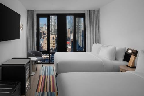 a hotel room with a bed and a large window at Aloft New York Chelsea in New York