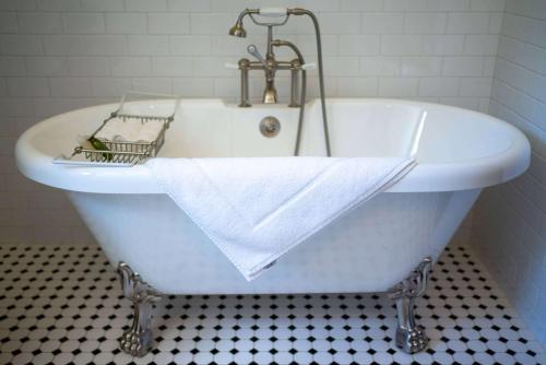 Sheridan Inn - Best Western Signature Collection في شيريدان: حوض استحمام أبيض مع منشفة في الحمام