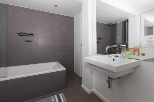 bagno con lavandino, vasca e specchio di Cosy Ground Floor Apartment a Londra