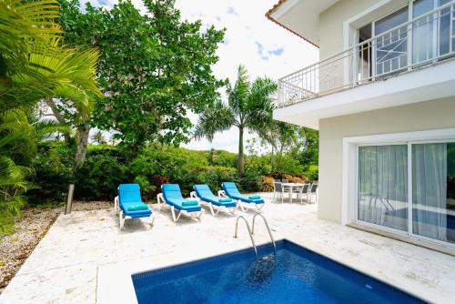 una piscina con sillas azules y una casa en Luxury Villa Iberosta - 4BDR, Private Beach, Pool & Jacuzzi, en Punta Cana